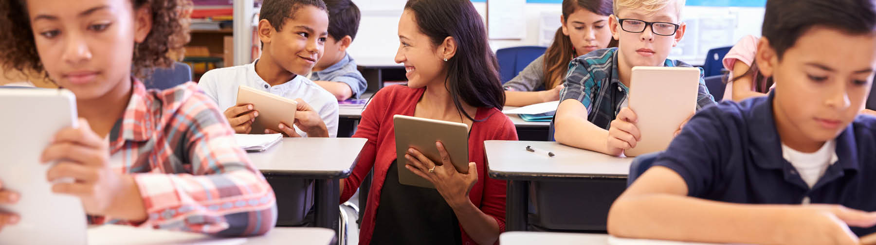 Teacher assists students in using a tablet