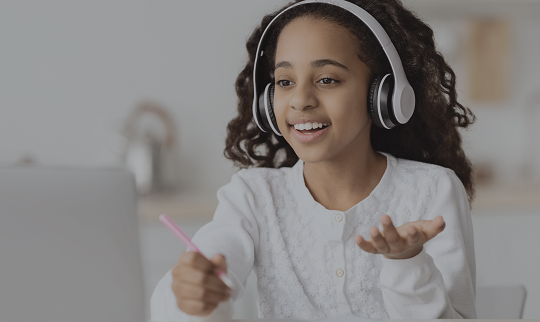 photo of a female student with headphones working on a laptop