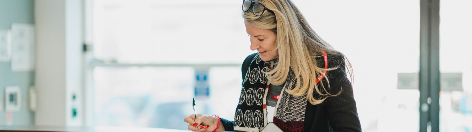 woman signing in at the front desk of a school 