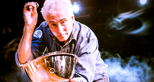 white haired man playing the drums on a steel mixing bowl