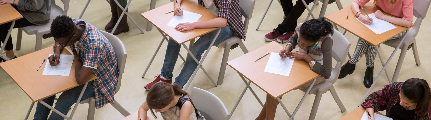 photo of a high school classroom taken from above showing rows of desks with students taking a test