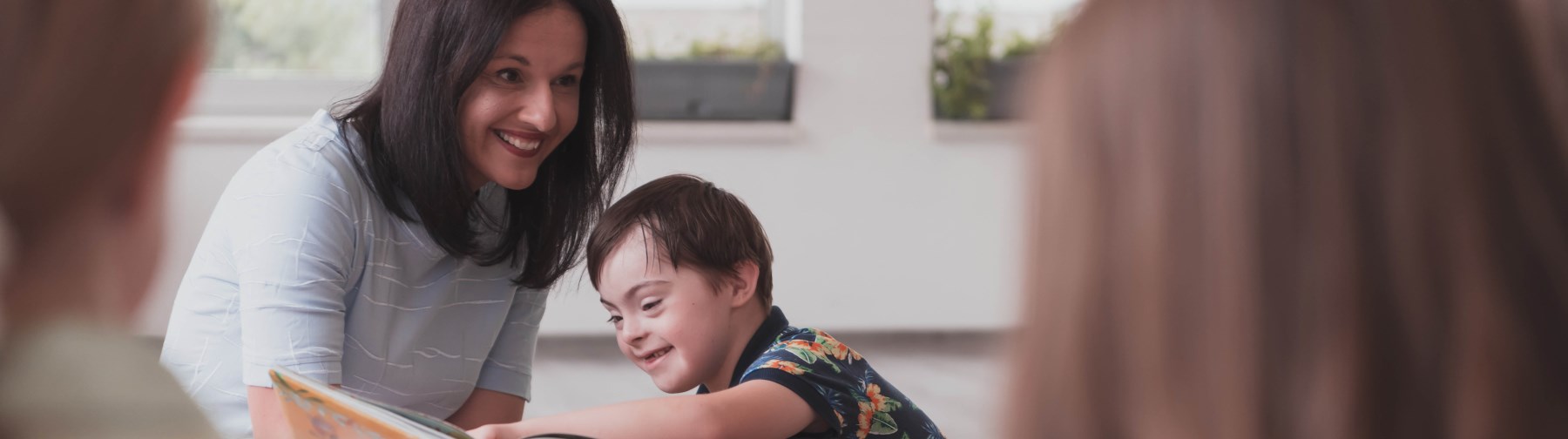 female teacher sitting on the floor reading to a young male student